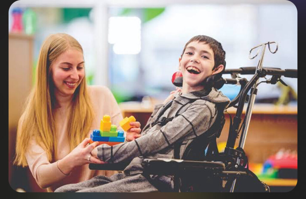 A boy in a wheelchair smiling at the camera.